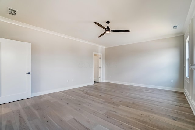 empty room featuring visible vents, crown molding, baseboards, and wood finished floors