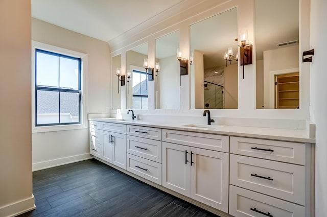 bathroom featuring visible vents, a sink, a shower stall, and wood finished floors