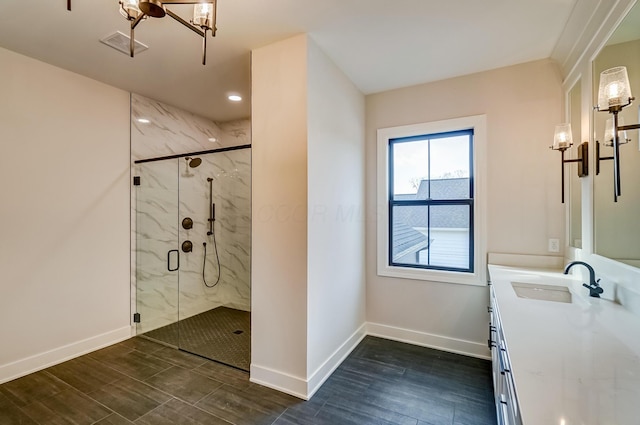 bathroom with a marble finish shower, baseboards, visible vents, wood finished floors, and vanity