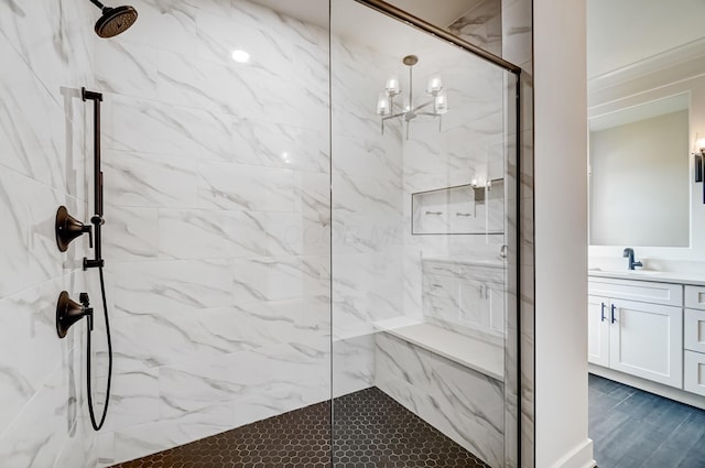 bathroom with vanity, a marble finish shower, and an inviting chandelier