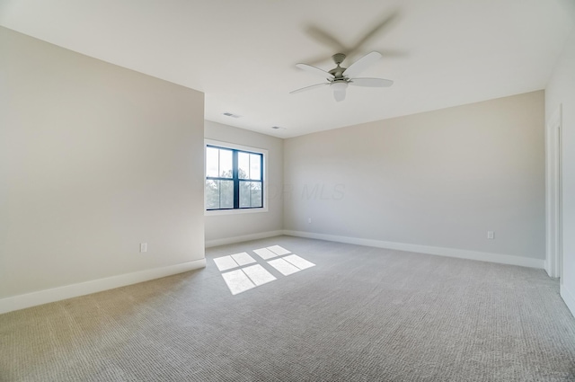 empty room featuring light carpet, ceiling fan, visible vents, and baseboards