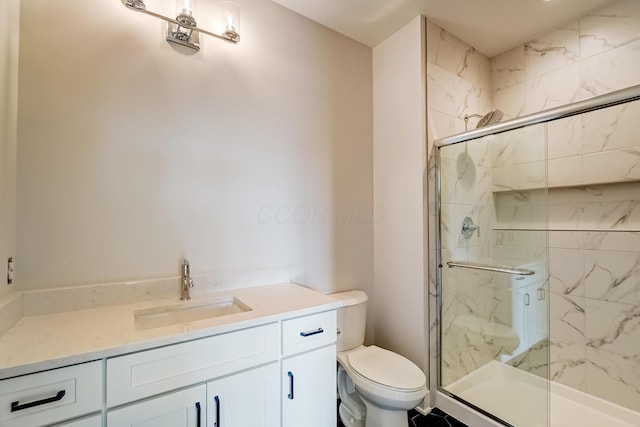 bathroom featuring toilet, vanity, and a marble finish shower