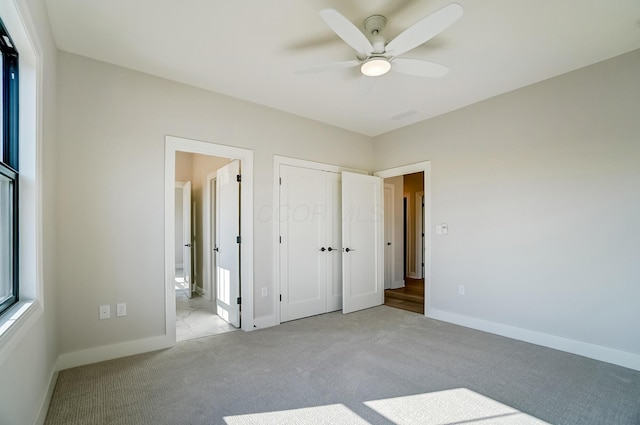 unfurnished bedroom featuring carpet floors, ensuite bath, a ceiling fan, and baseboards