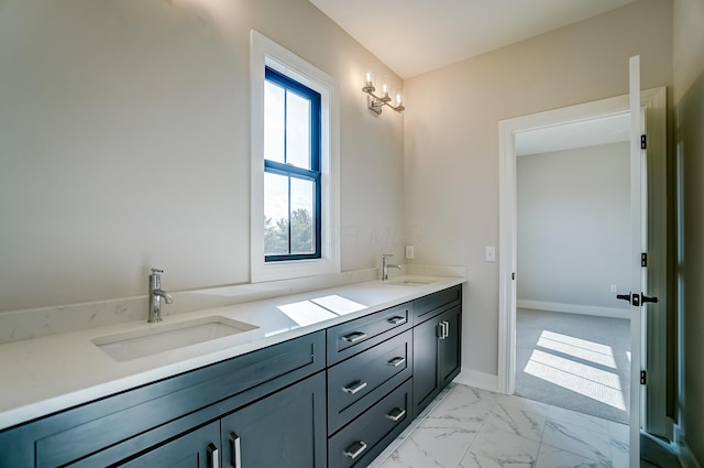 full bathroom with marble finish floor, a sink, baseboards, and double vanity