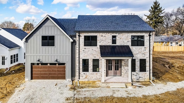 modern farmhouse style home featuring an attached garage, board and batten siding, a standing seam roof, metal roof, and stone siding