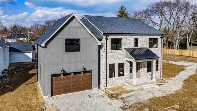 modern inspired farmhouse with board and batten siding, stone siding, roof with shingles, and an attached garage