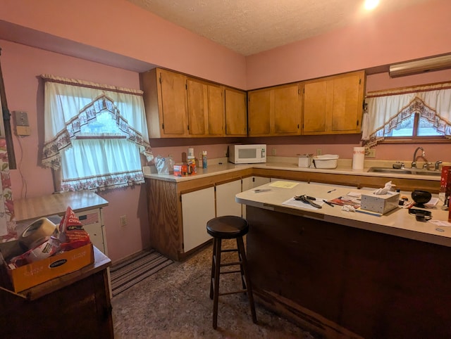 kitchen featuring a textured ceiling, a kitchen bar, and sink