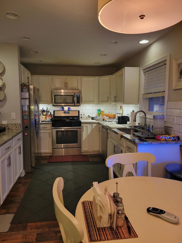 kitchen with dark stone counters, sink, decorative backsplash, appliances with stainless steel finishes, and white cabinetry