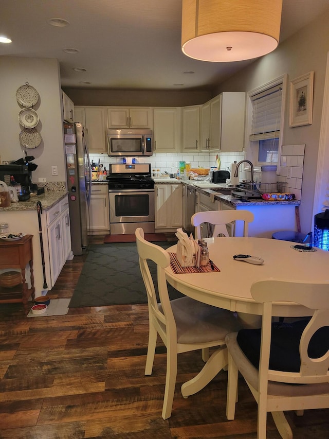 kitchen featuring dark wood-type flooring, sink, appliances with stainless steel finishes, tasteful backsplash, and white cabinetry