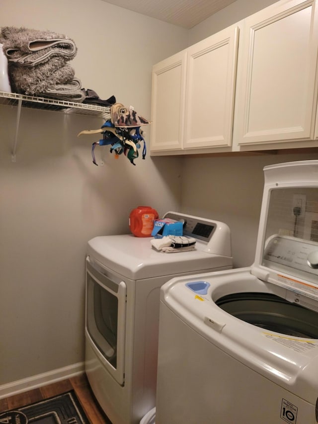 washroom featuring separate washer and dryer, dark hardwood / wood-style flooring, and cabinets