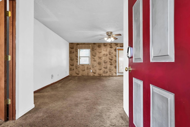 foyer entrance with ceiling fan, dark carpet, and a textured ceiling