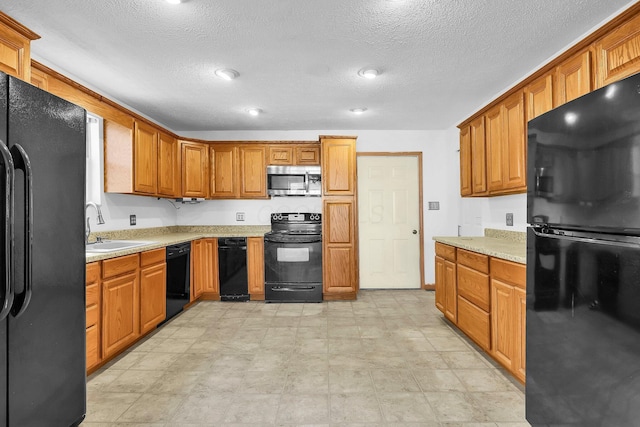 kitchen with black appliances, light stone countertops, sink, and a textured ceiling