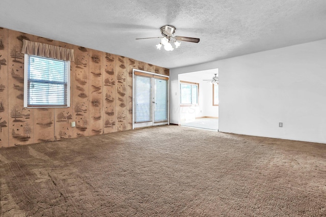 carpeted spare room with a textured ceiling, a wealth of natural light, and ceiling fan