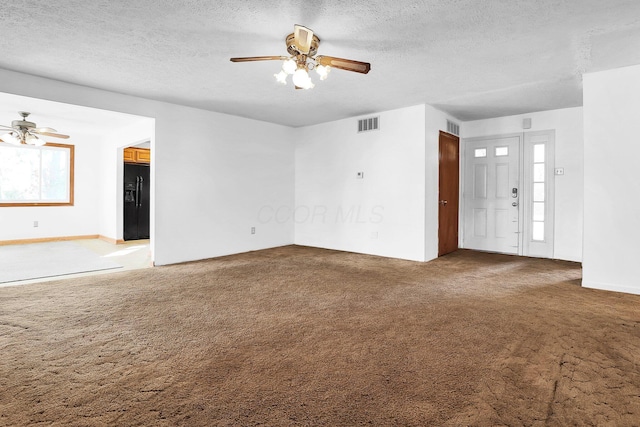 unfurnished living room featuring carpet, ceiling fan, and a textured ceiling