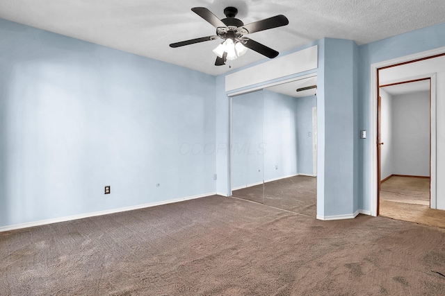 unfurnished bedroom with dark colored carpet, ceiling fan, and a textured ceiling