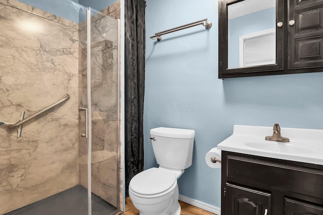 bathroom with a tile shower, vanity, and toilet