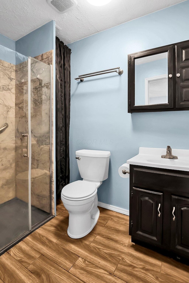 bathroom with tiled shower, hardwood / wood-style floors, a textured ceiling, and vanity