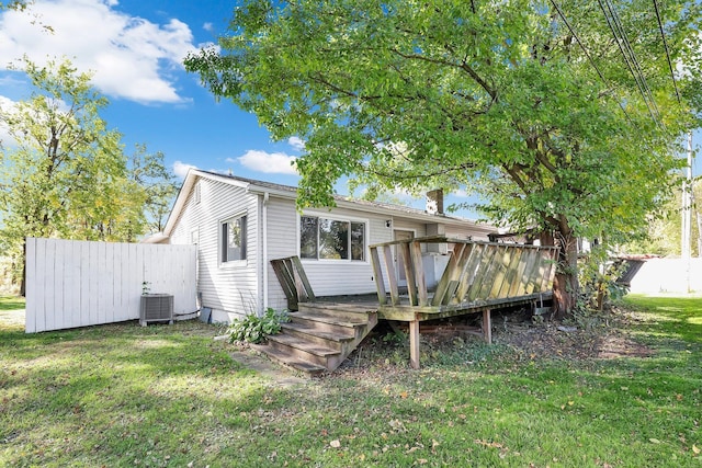 rear view of property with central air condition unit, a wooden deck, and a yard