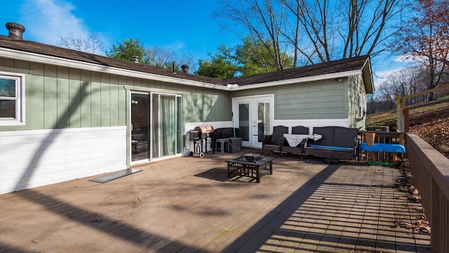 wooden deck with french doors and an outdoor living space with a fire pit