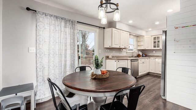 dining area featuring sink, dark wood-type flooring, and an inviting chandelier