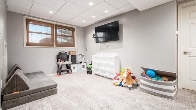 recreation room featuring a drop ceiling and carpet floors