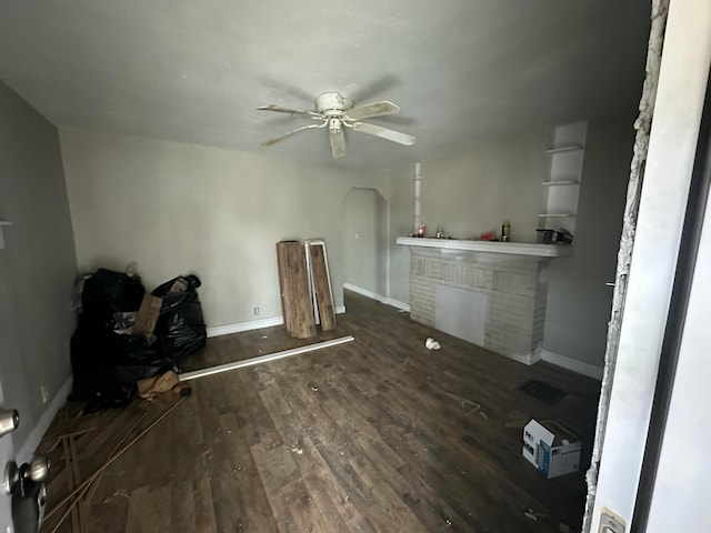 unfurnished living room featuring dark hardwood / wood-style floors, ceiling fan, and a fireplace