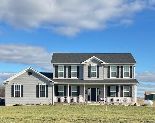 colonial inspired home with a porch and a front yard