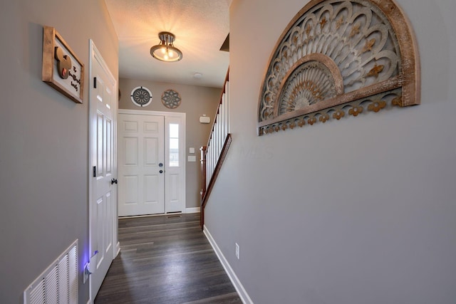 foyer entrance with dark hardwood / wood-style flooring and a textured ceiling