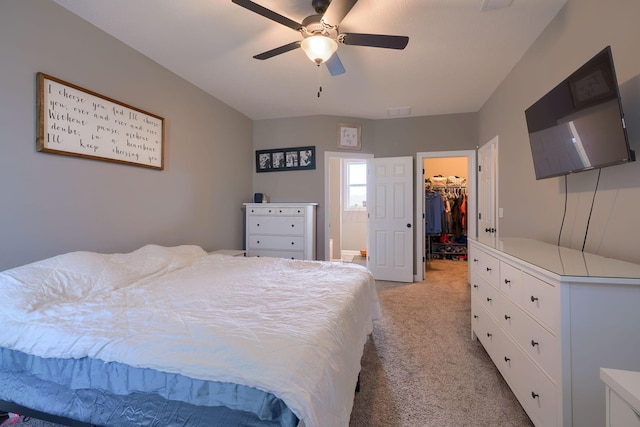 bedroom with a spacious closet, light carpet, ceiling fan, and a closet