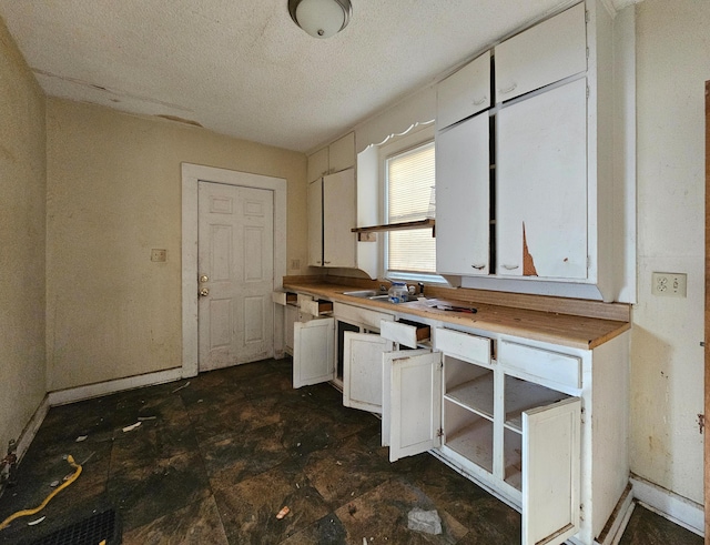 kitchen featuring white cabinetry, sink, wooden counters, and a textured ceiling