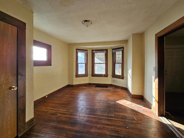 spare room featuring a textured ceiling and dark wood-type flooring