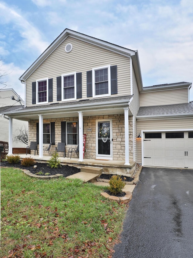 view of front of property with a front yard, a porch, and a garage