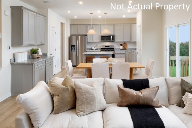 kitchen featuring stainless steel appliances, a center island, open floor plan, and gray cabinetry