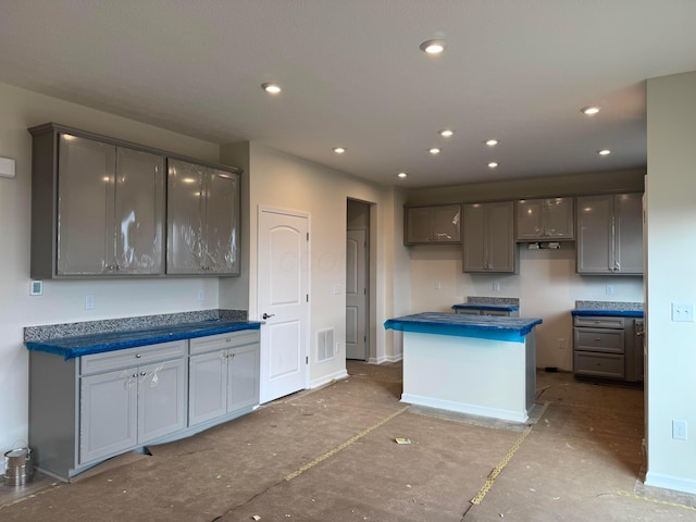 kitchen featuring visible vents, baseboards, dark countertops, a center island, and recessed lighting