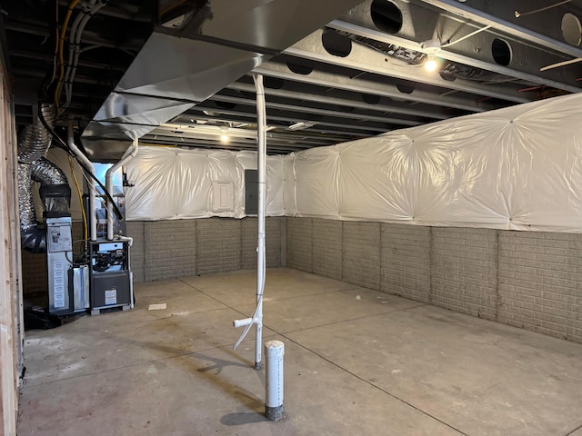 unfinished basement featuring brick wall and heating unit