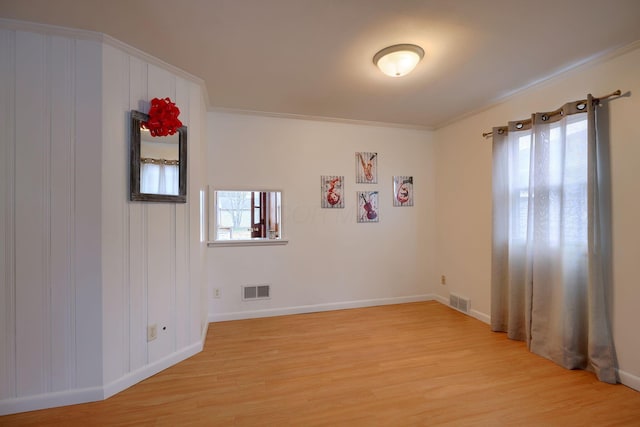 spare room featuring ornamental molding, a healthy amount of sunlight, and light hardwood / wood-style floors