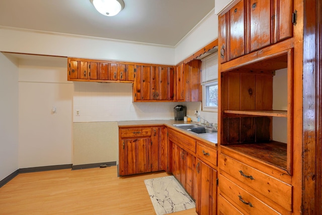 kitchen featuring decorative backsplash, light hardwood / wood-style flooring, ornamental molding, and sink