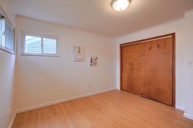 unfurnished bedroom featuring a closet, light hardwood / wood-style flooring, and crown molding