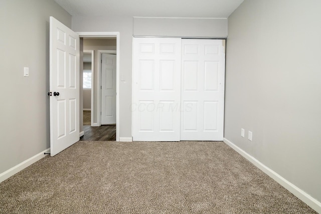 unfurnished bedroom featuring a closet and dark carpet