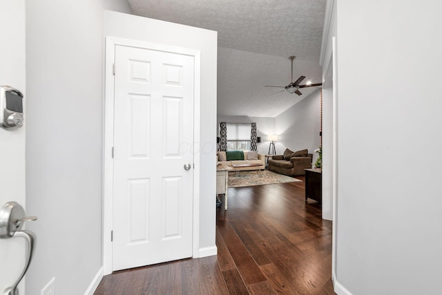 corridor featuring a textured ceiling, vaulted ceiling, and dark hardwood / wood-style floors