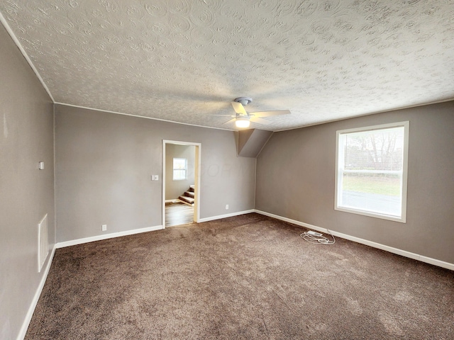 additional living space featuring carpet flooring, a textured ceiling, vaulted ceiling, and ceiling fan