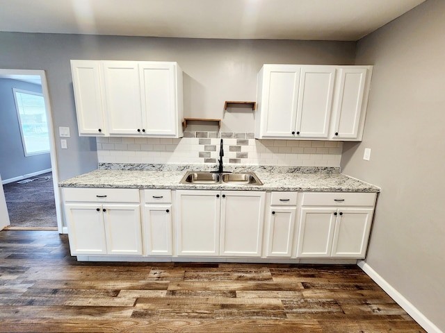 kitchen with light stone countertops, sink, tasteful backsplash, dark hardwood / wood-style floors, and white cabinets