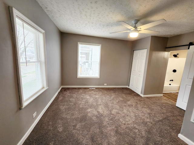 unfurnished bedroom featuring ceiling fan, a textured ceiling, and dark colored carpet