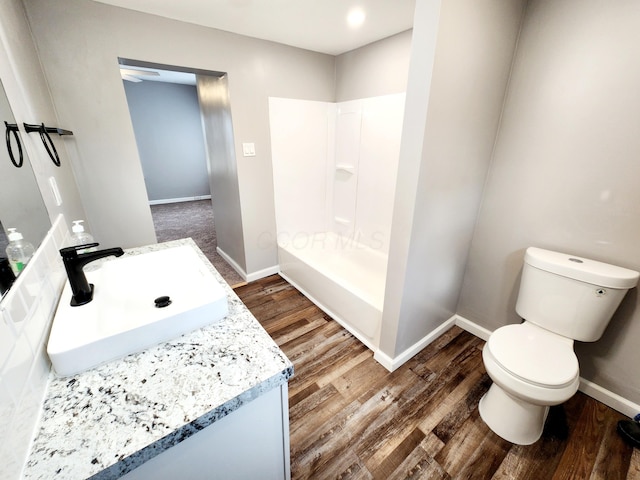 bathroom with walk in shower, toilet, vanity, and hardwood / wood-style flooring