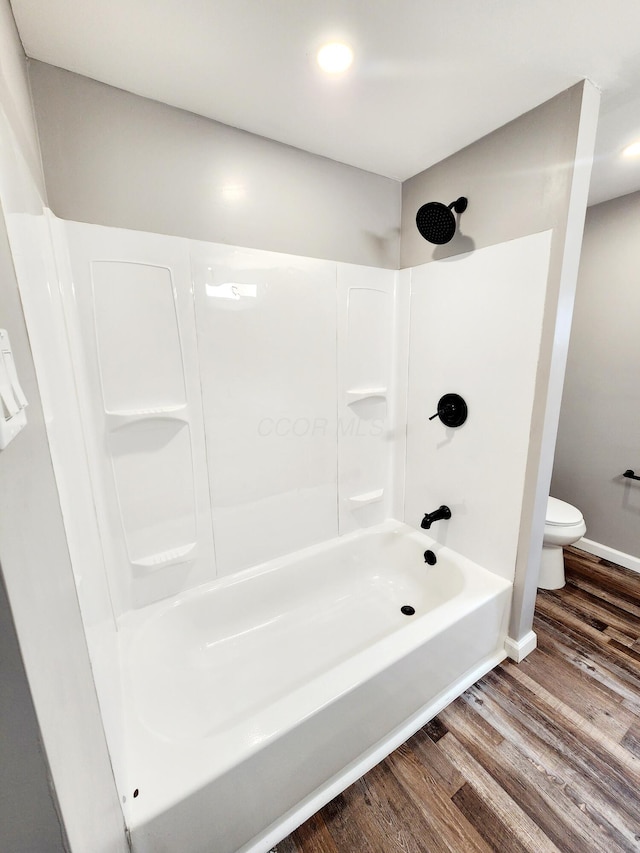 bathroom featuring shower / bathing tub combination, wood-type flooring, and toilet