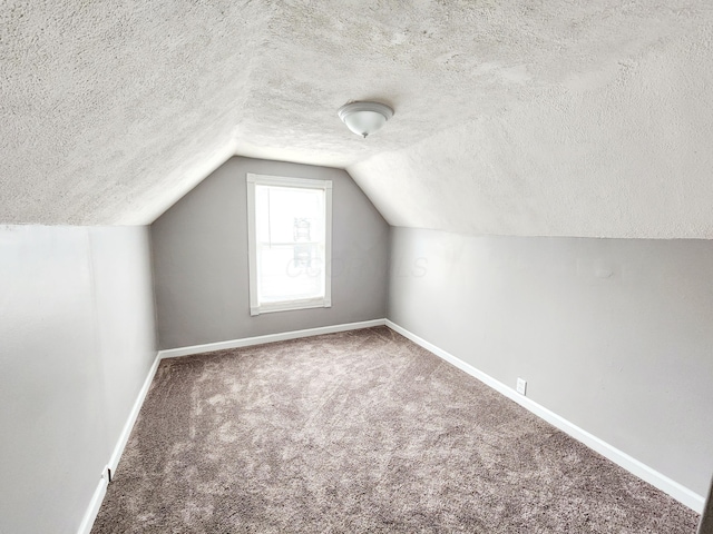 additional living space featuring carpet flooring, lofted ceiling, and a textured ceiling