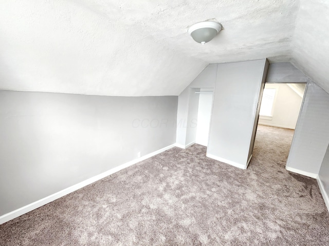 bonus room with carpet flooring, lofted ceiling, and a textured ceiling