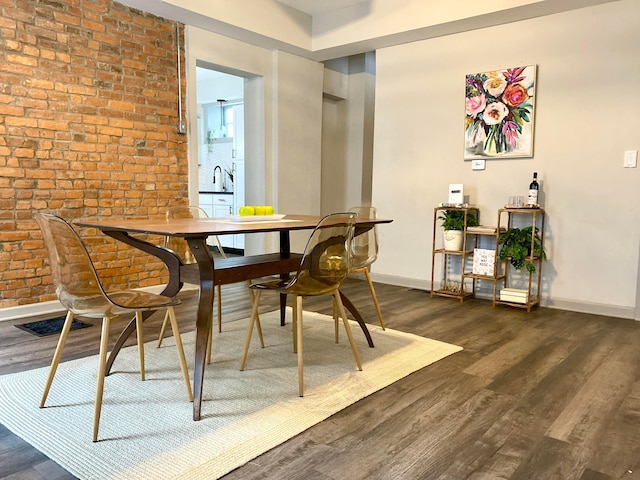 dining area with brick wall and dark hardwood / wood-style flooring