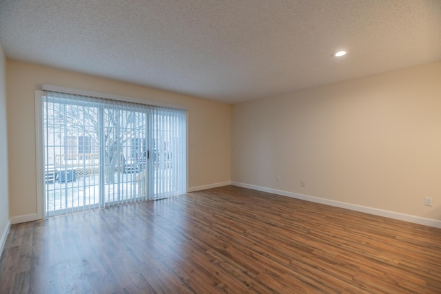 empty room with a textured ceiling and dark hardwood / wood-style flooring