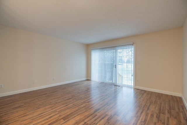 spare room with a textured ceiling and dark hardwood / wood-style floors